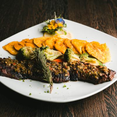 Skirt Steak topped with chimichurri sauce and served with tostones and broccoli.