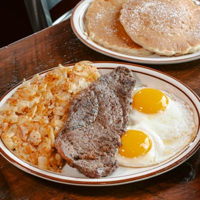 A New York Strip steak served with two eggs and a side of hash browns..