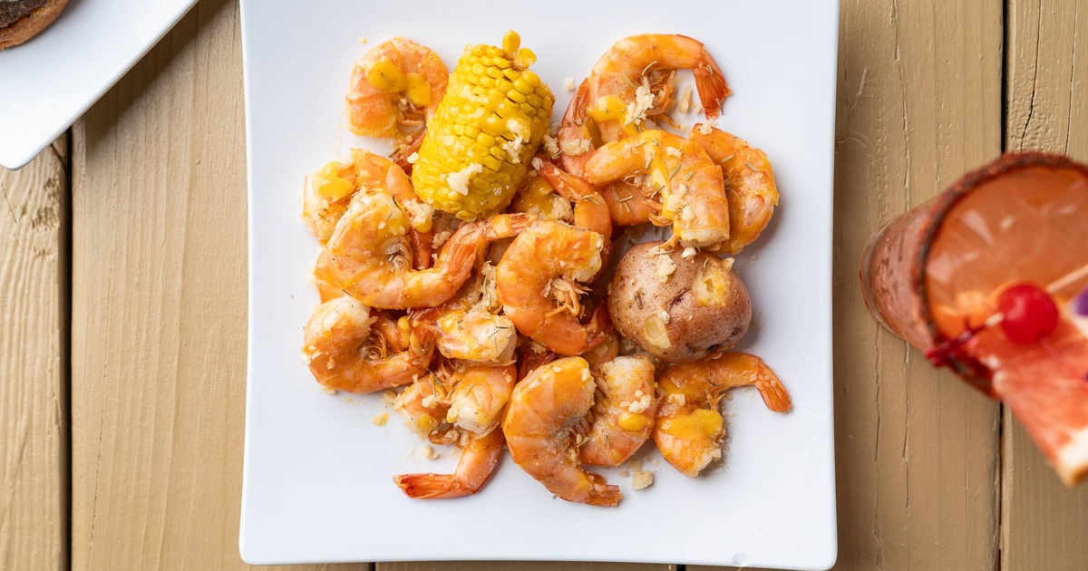 Boiled shrimp with corn and potato served with a cocktail