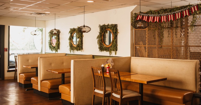 Restaurant booths by a wall decorated with dried wreath mirrors