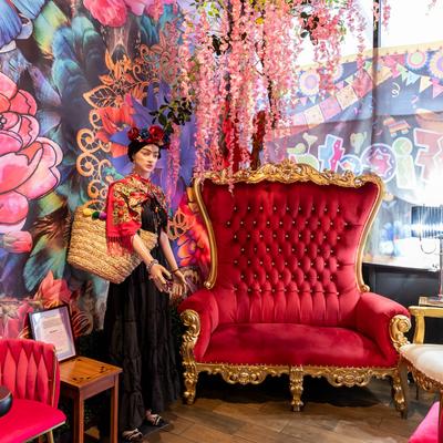 Vibrant room with a red throne chair, flower decorations, and Frida Kahlo statue.