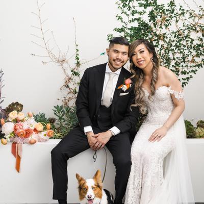 The bride and groom posing for a photo with their dog.