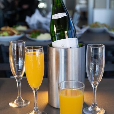 A Mimosa cocktail set, a bottle of sparkling wine in a cooler and champagne flutes.