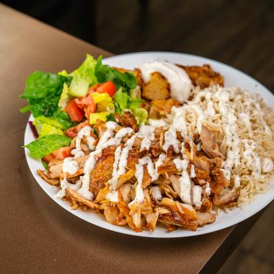 Chicken shawarma served with rice, salad, and potatoes.