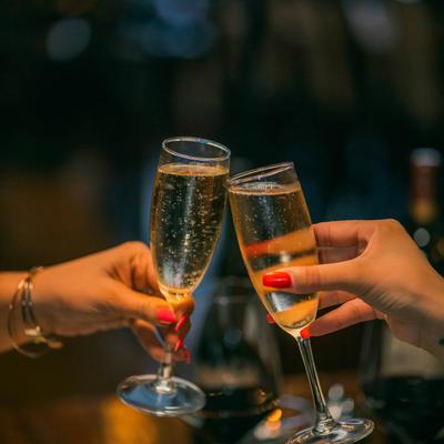 Two people toast with white wine, hand shot.