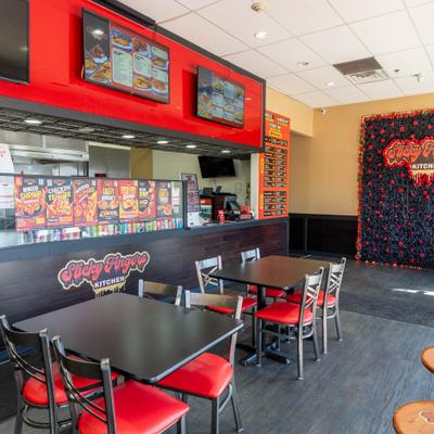 Interior with a counter, tables, chairs and  floral wall with the restaurant's sign.