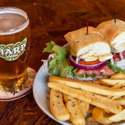 Turkey, Green Apple & Brie sandwich and fries, accompanied with a beer.