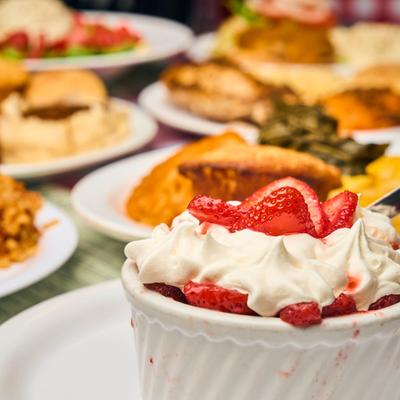 Strawberry Shortcake topped with whipped cream and strawberries and other dishes in the background.