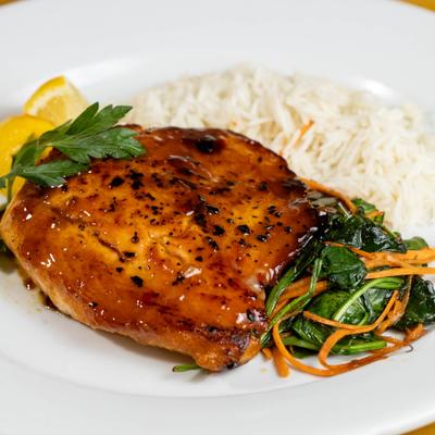 Glazed salmon served with rice, vegetables and lemon wedges.