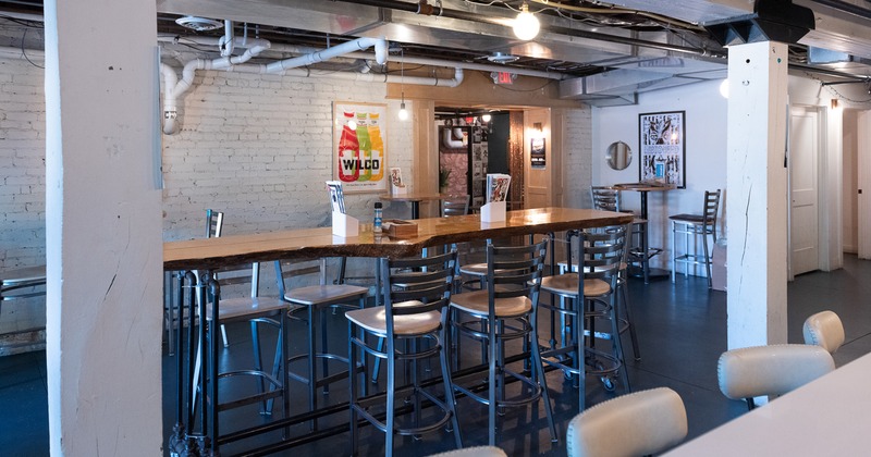 Modern and spacious industrial-style dining area with a long wooden table and bar stools