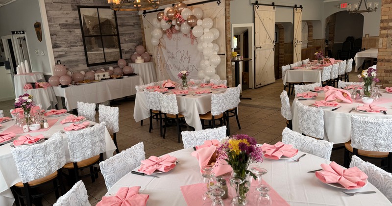 Fully set tables with floral centerpieces and pink napkins