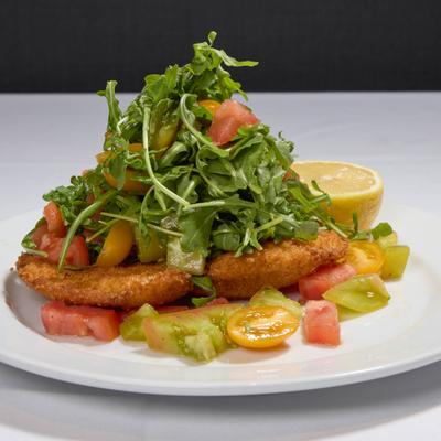 Breaded chicken breast topped with arugula and tomatoes.