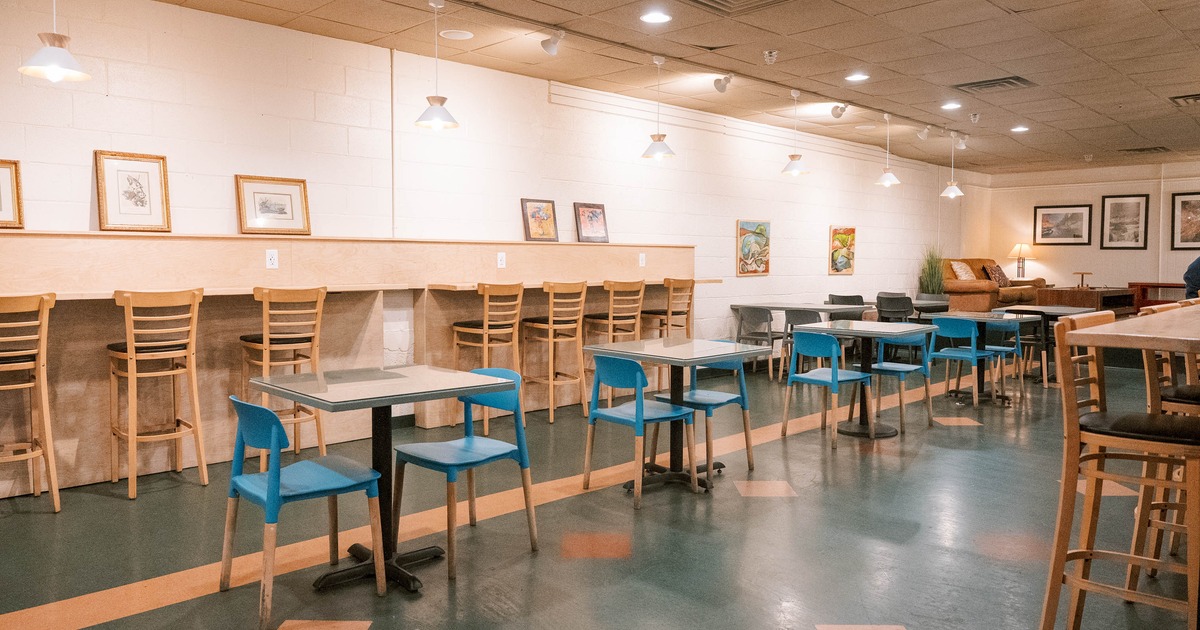 Indoor - wooden and blue seating, framed art on white walls and a cozy seating area in the back