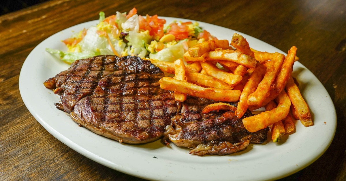 Ribeye steak served with fries and a salad