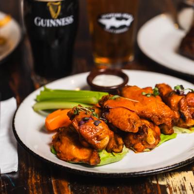 Buffalo wings served with celery sticks, carrots, ranch sauce, and a beer.
