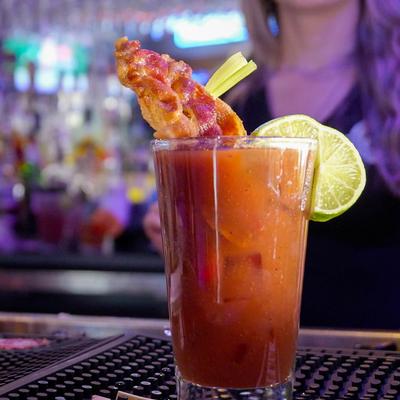 A glass of Bloody Mary sitting on a bar counter.