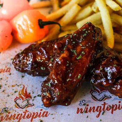 Wings covered with sauce and fries, closeup