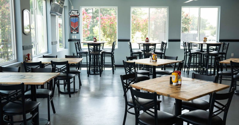 Interior, regular and high seating area with padded chairs and stools, large windows