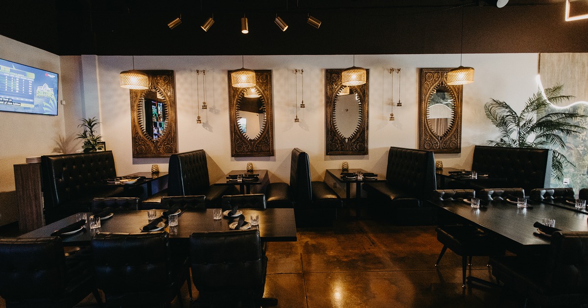 Modern interior dining area with dark upholstered dining booths and chairs, and set dining tables