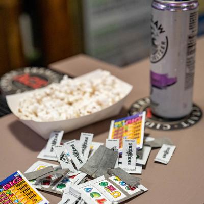 Scratch off game tickets on the table with popcorn and hard seltzer can.