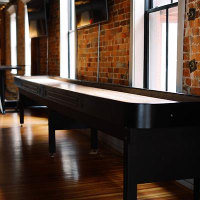 Long shuffleboard table in a brick-walled room.