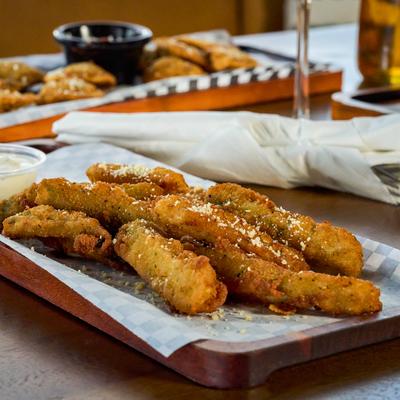 Zucchini sticks with dipping sauce on a tray.