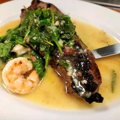 Filet mignon topped with creamed spinach, accompanied by a single shrimp.