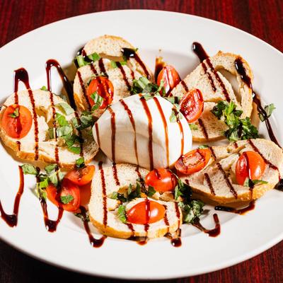 Burrata cheese with toasted bread, grape tomatoes, basil, and balsamic glaze.