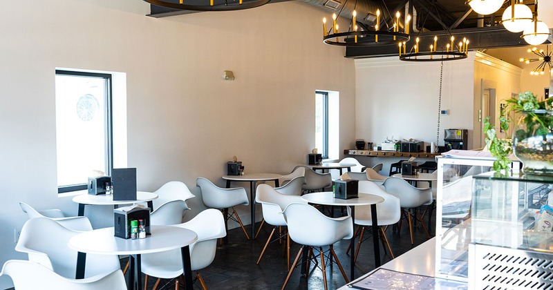 Interior, white tables and white arm chairs, wagon wheel ceiling lights