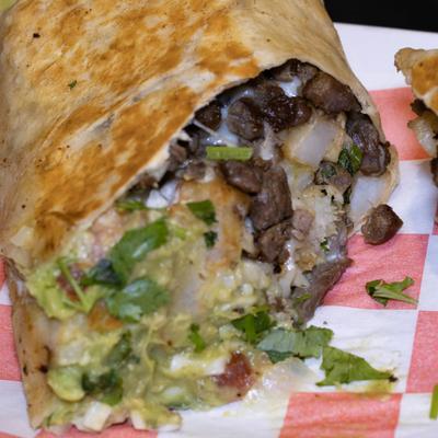 Beef burrito with tomatoes, onions, cilantro, and guacamole.