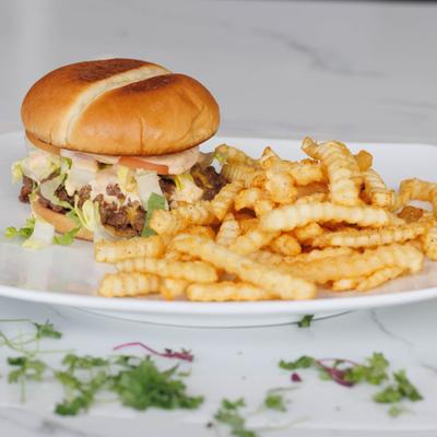 Cheeseburger served with crinkle cut fries on a white plate.