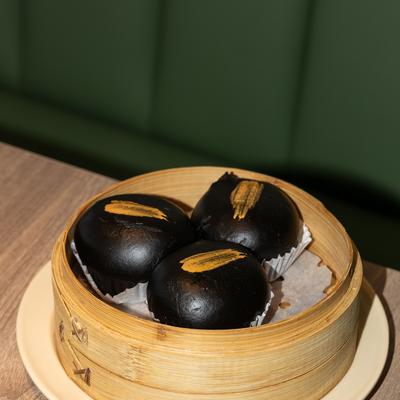 Black Gold Lava Bun in a bamboo steamer.