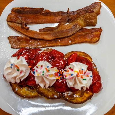 Classic French toast served with strawberry sauce, whipped cream and bacon.