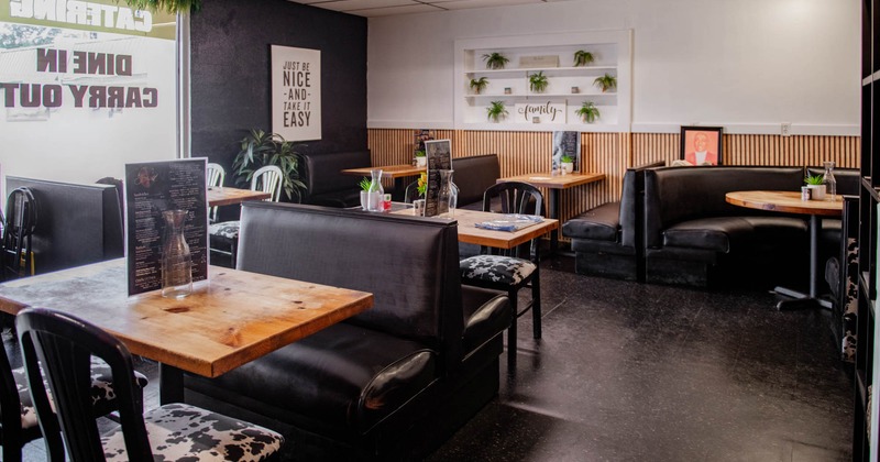 Interior, wooden top tables, black leather padded booths, large shop window