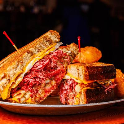 The Kirby, corned beef sandwich on grilled rye bread, served with onion rings.