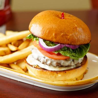 Burger with lettuce, tomato, and onion, served with fries.