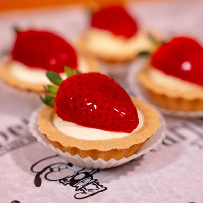 Mini fruit tarts, each topped with a strawberry, close up shot.