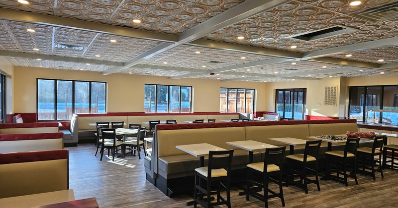 Interior of modern restaurant with tables, chairs, booths, and large windows