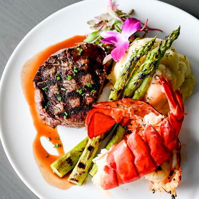Grilled steak served with lobster tail, asparagus, and mashed potatoes.
