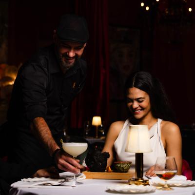 Server placing a cocktail for guests during dinner service.