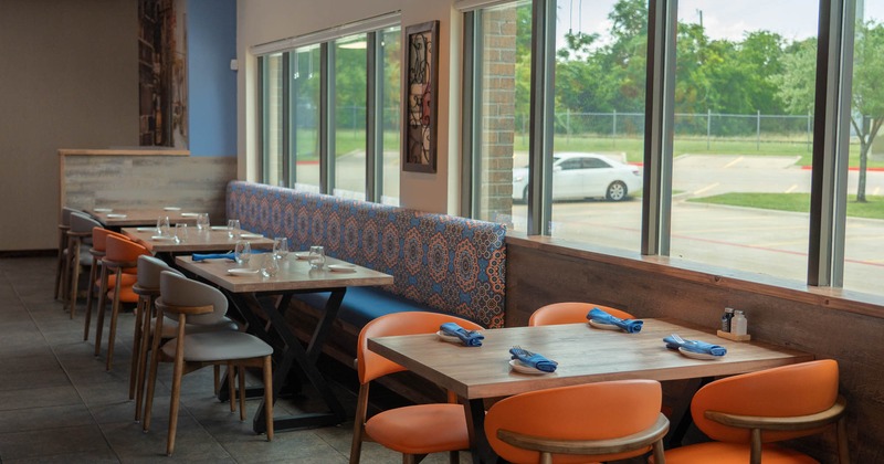 Interior, dining area, long banquette bench with tables and chairs, single table for four