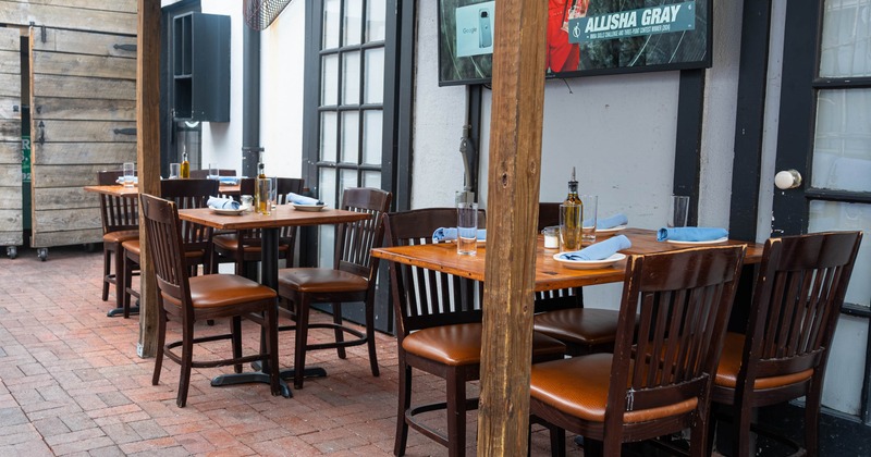 Outdoor dining area with wooden tables and chairs, blue napkins, and a TV
