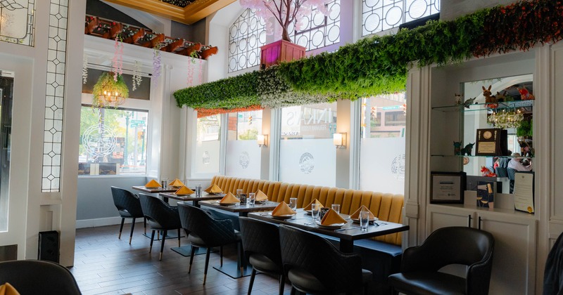 A restaurant interior with a yellow banquette, black chairs, and tables