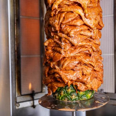 Marinated meat roasting vertically with a pineapple.
