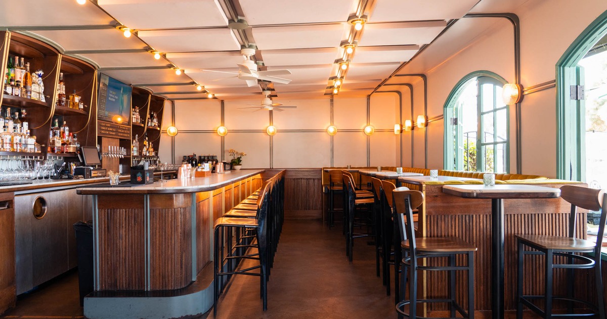Interior featuring a wooden bar, stools, and large windows