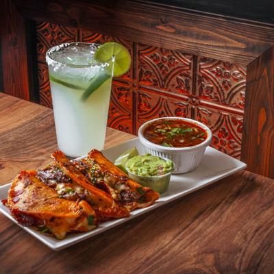 Birria tacos with guacamole and consomme, alongsid a Margarita cocktail.