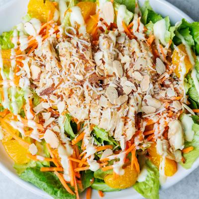 Grilled chicken salad with lettuce, mandarin oranges, toasted almonds, and carrots.
