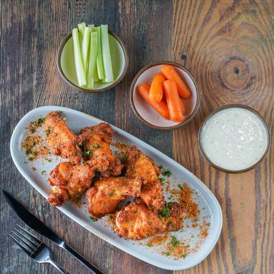Chicken wings with celery, carrots, and a sauce.