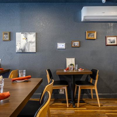 Interior with table seating and dark gray walls decorated with small framed artworks.