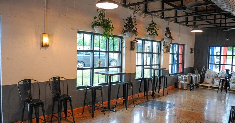 Interior, seating area by windows, tall bar tables and stools